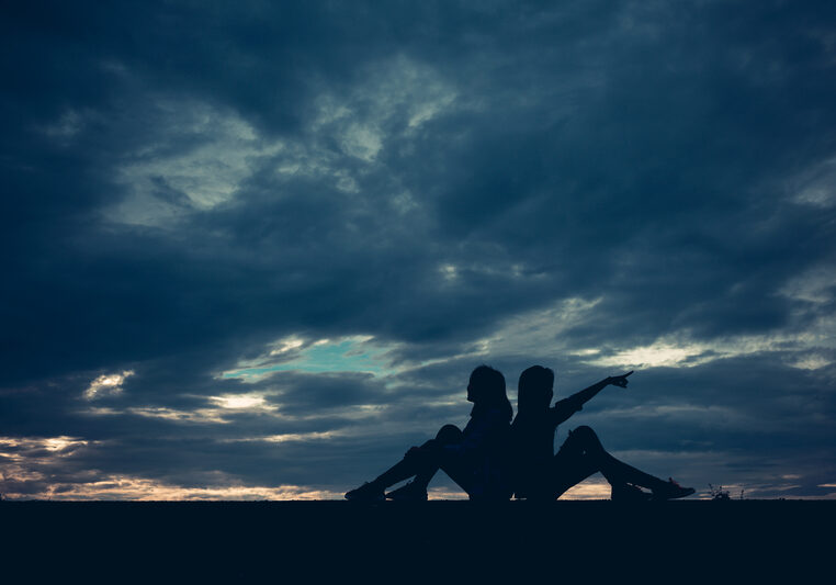 Two Women leaning back-to-back